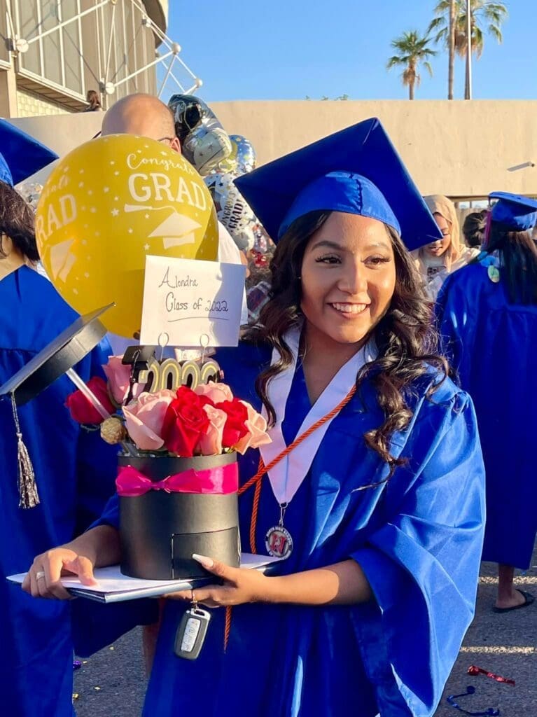 Alondra celebrates her graduation in a blue cap and gown, marking an important educational milestone and achievement.