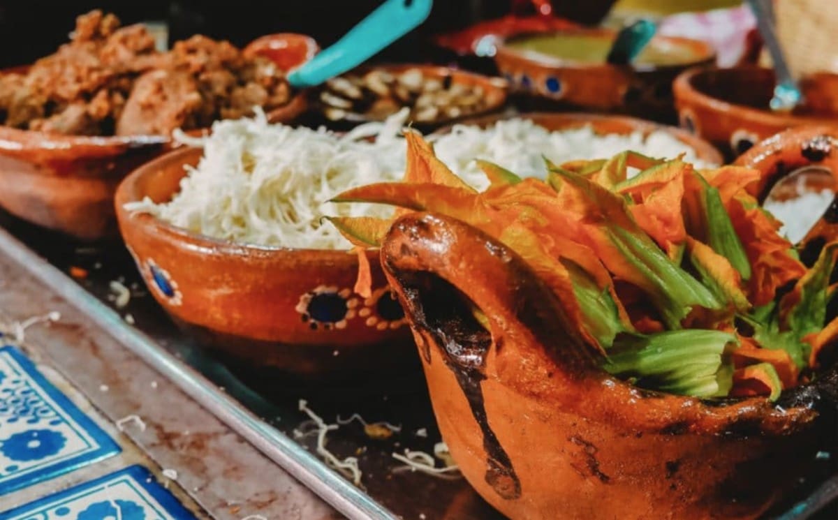 Traditional Latin American dishes served in colorful clay bowls, featuring fresh vegetables, rice, and regional cuisine at a local restaurant.