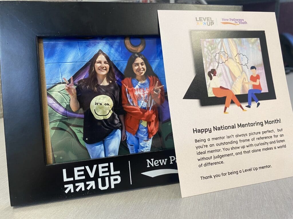 Level Up mentor appreciation display featuring a framed photo of students and a National Mentoring Month thank-you card
